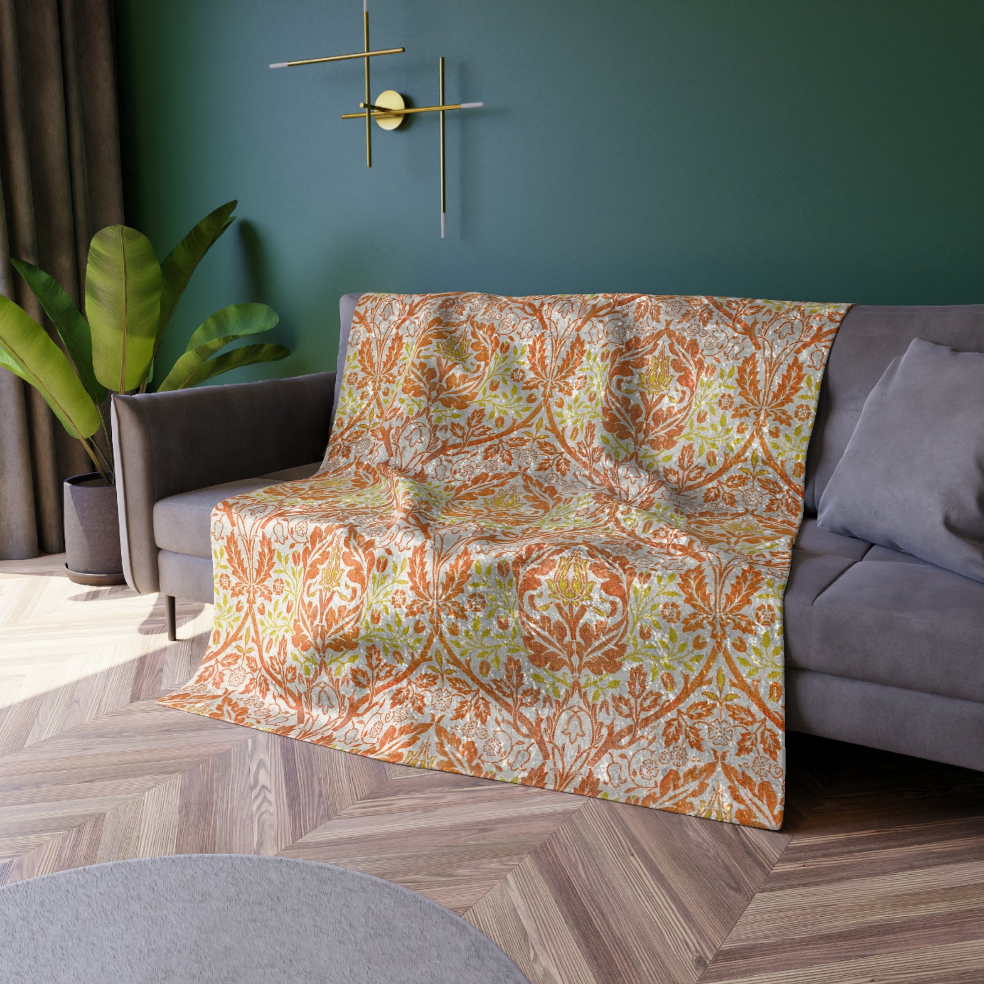 A crushed velvet blanket with a William Morris & Co floral pattern in shades of orange, yellow, and green on a white background, folded to show both the patterned side and the solid silky finish.