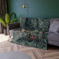 A lush crushed velvet blanket with a greenery design, inspired by William Morris, with hemmed edges and a silky finish.