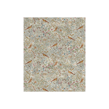 A plush, floral patterned velvet blanket in shades of green, pink, and brown with hemmed edges.