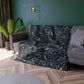 Patterned throw blanket draped over a sofa in a living room with a green wall and plant.