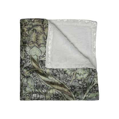 A crushed velvet blanket with a floral pattern in muted colors, folded to show both the patterned side and the solid gray reverse.