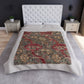 A crushed velvet blanket with a William Morris floral pattern in red and green colours, laid flat with hemmed edges visible.