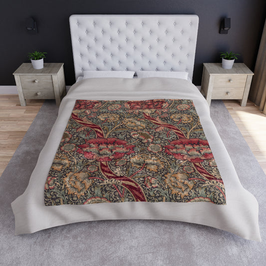 A crushed velvet blanket with a William Morris floral pattern in red and green colours, laid flat with hemmed edges visible.