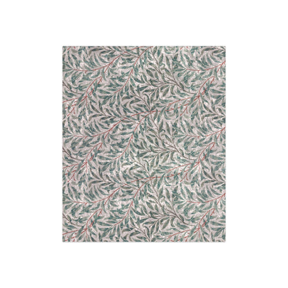 A crushed velvet blanket with a floral pattern in green and red on a white background, hemmed edges, and a silky finish.