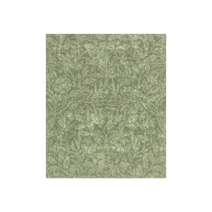 A green crushed velvet blanket with a floral pattern, folded neatly, with the silky reverse side partially visible.