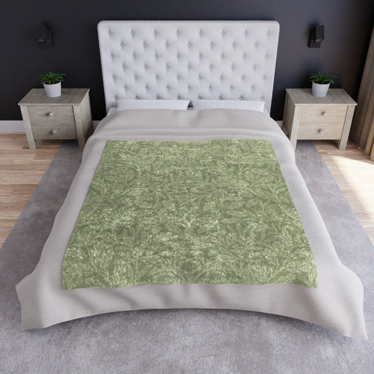 A green crushed velvet blanket with a William Morris & Co floral pattern, folded neatly, with the silky reverse side partially visible.