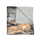 A crushed velvet blanket with a geometric pattern in a mix of dark and light colors, folded in half to show both sides.