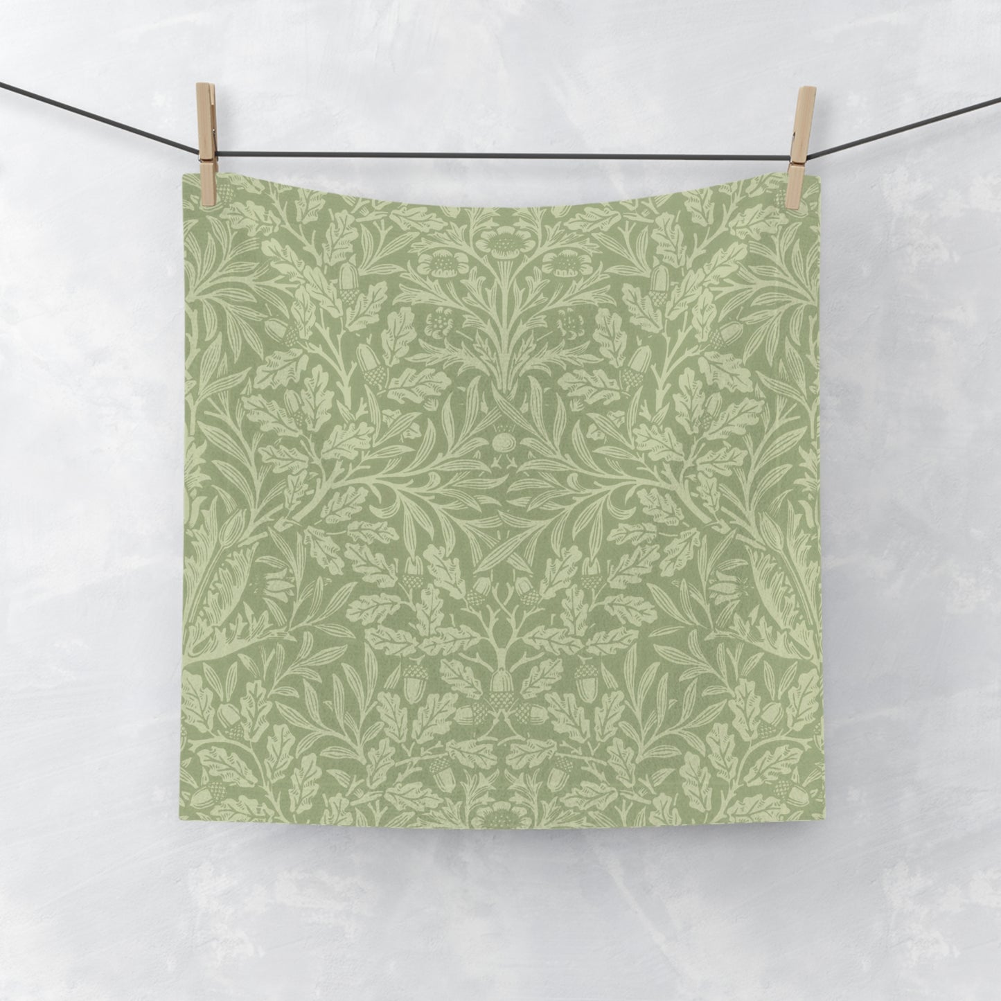 Green washcloth with a leaf pattern hanging on a clothesline against a white background