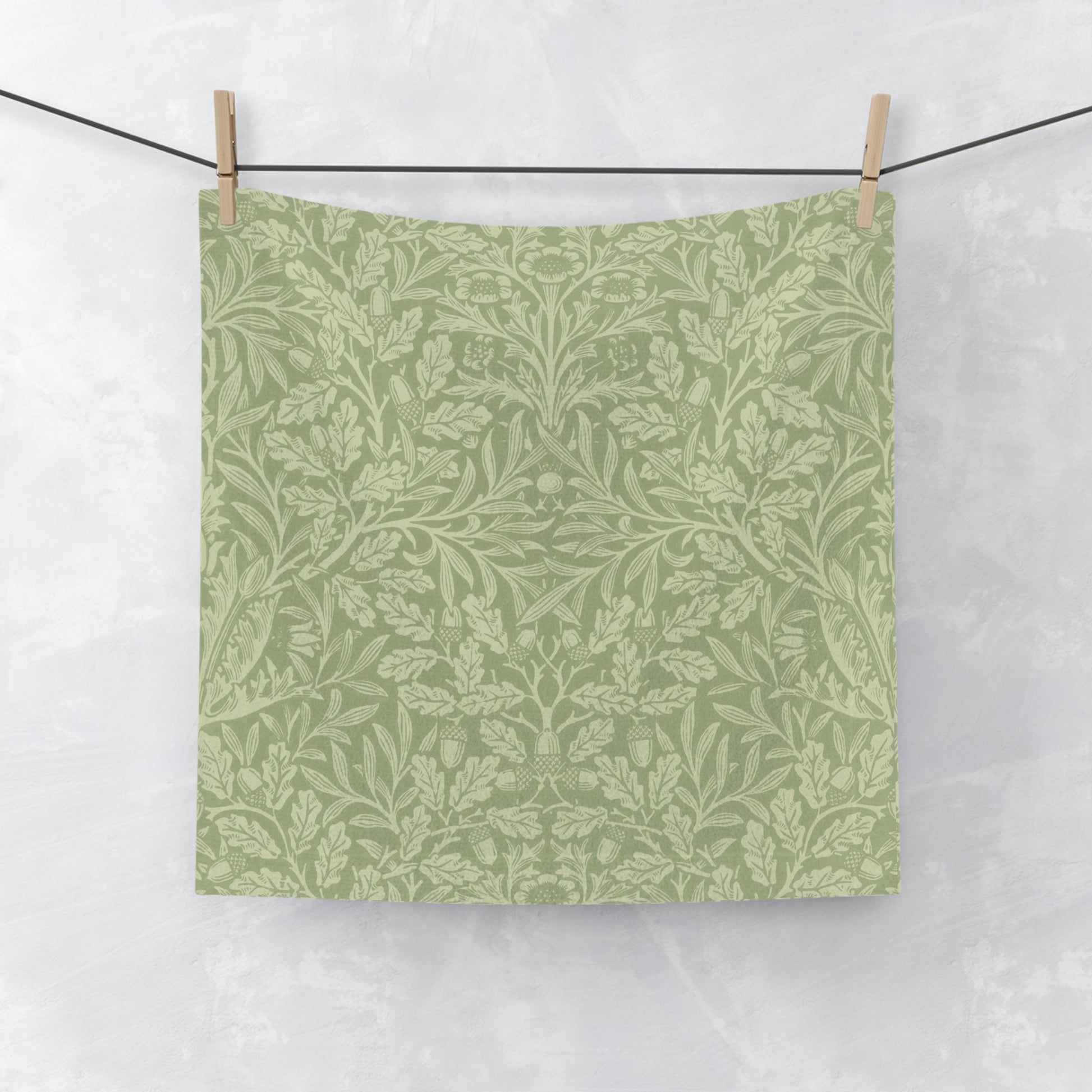 Green washcloth with a leaf pattern hanging on a clothesline against a white background