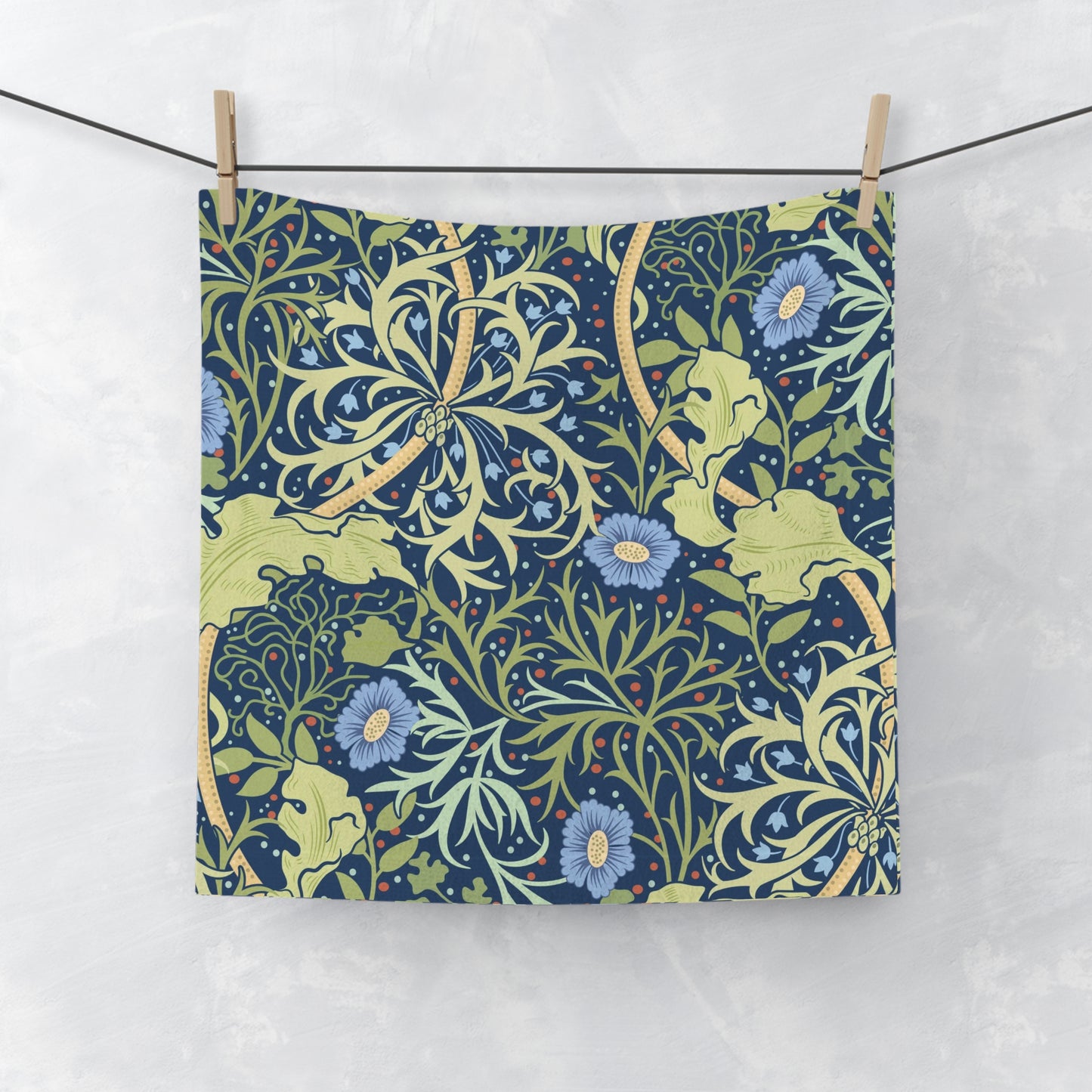 A white washcloth with a floral pattern inspired by William Morris, featuring blue flowers and green leaves on a yellow background.