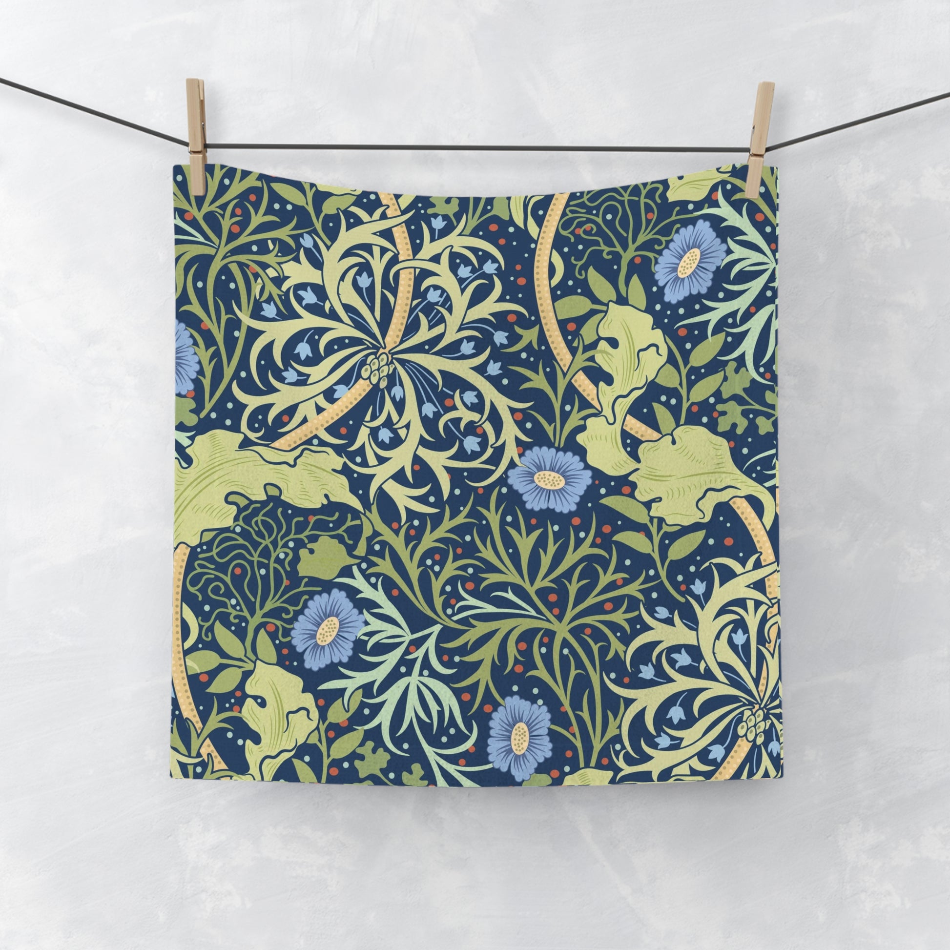 A white washcloth with a floral pattern inspired by William Morris, featuring blue flowers and green leaves on a yellow background.