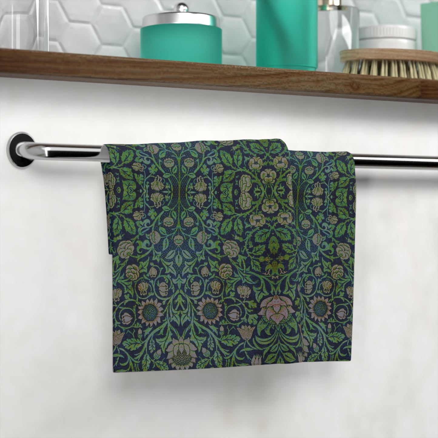 A green face cloth with floral William Morris & Co patterns hanging on a towel rack in a bathroom setting.