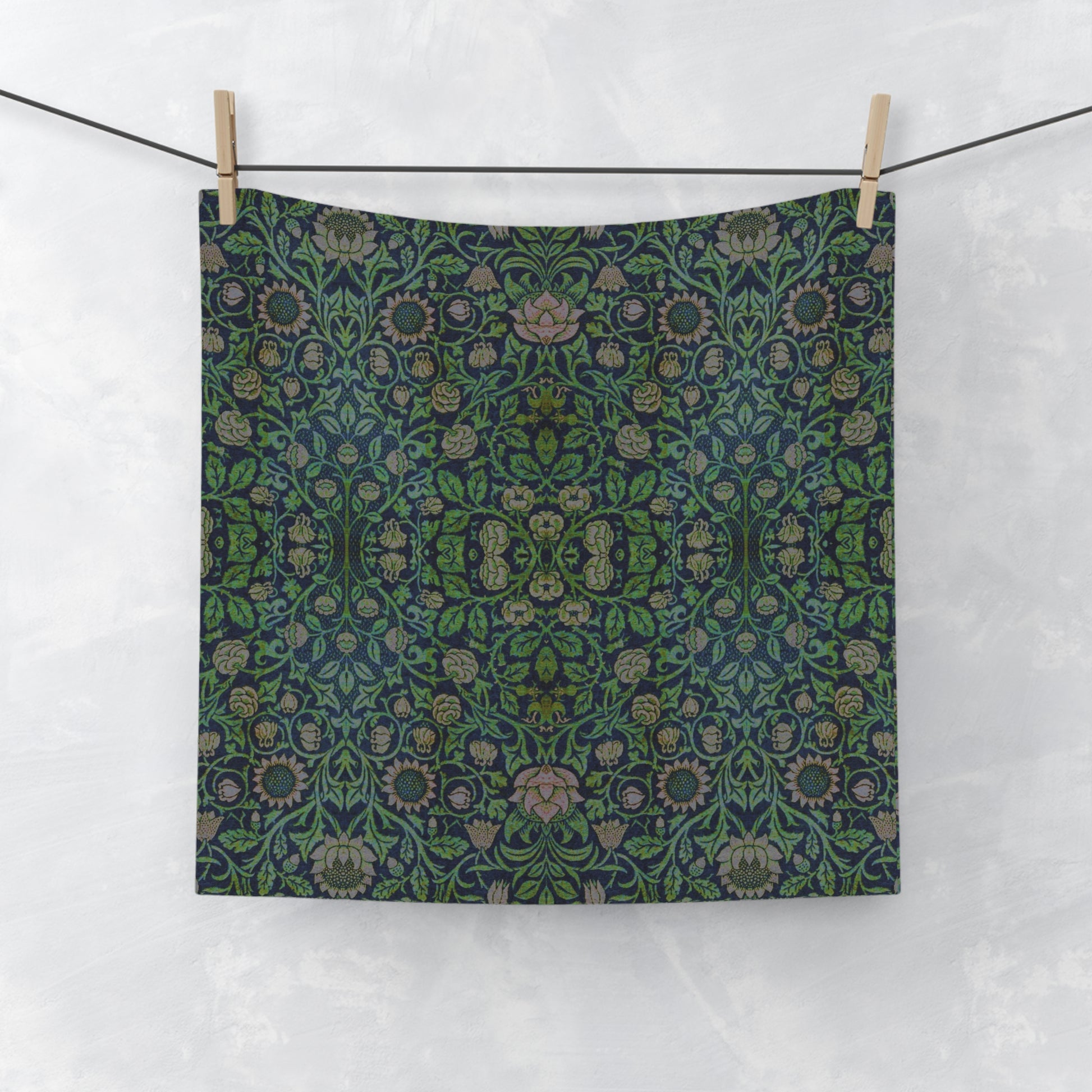A green face cloth with floral William Morris & Co patterns hanging on a towel rack in a bathroom setting.
