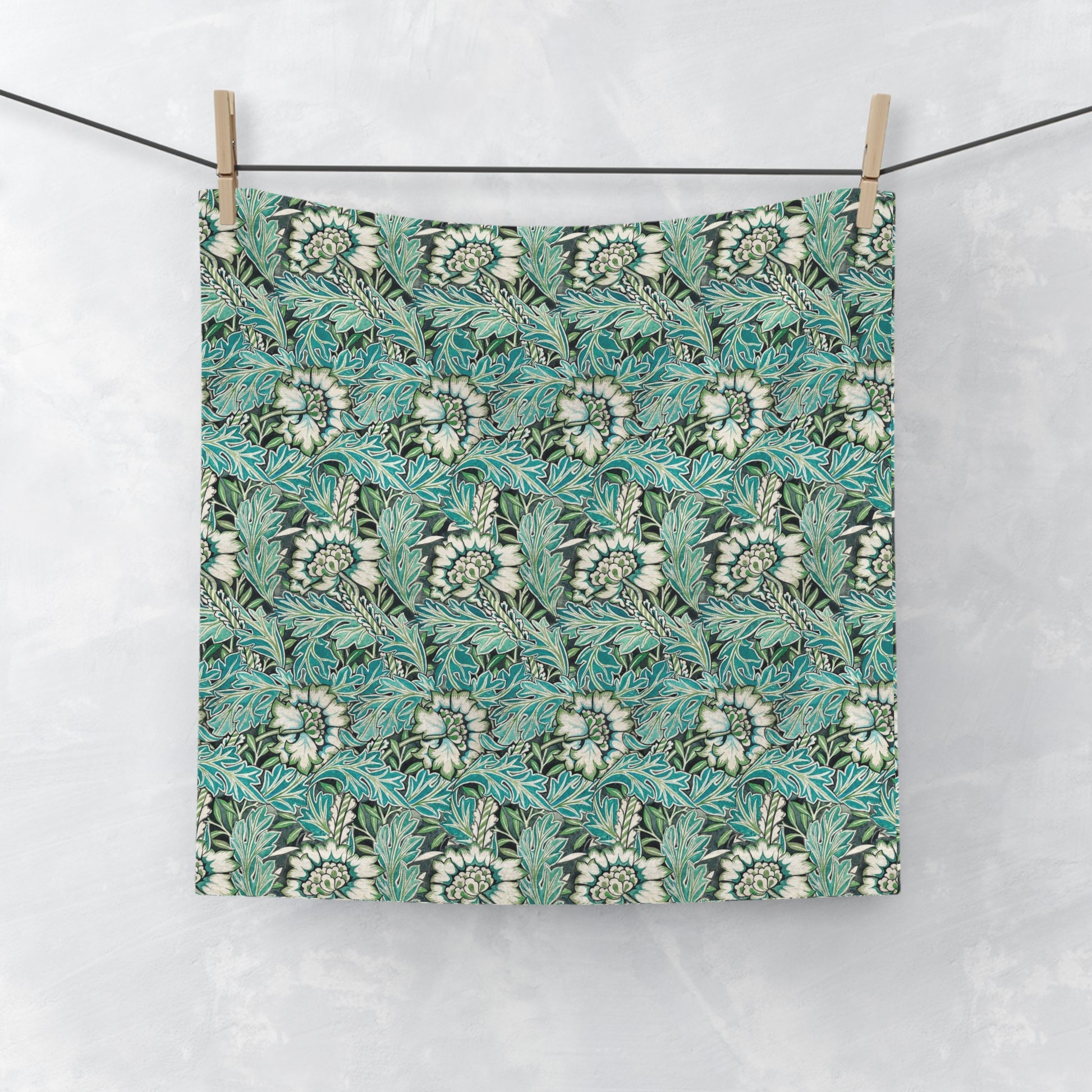 A white washcloth with a floral pattern inspired by William Morris, featuring green and blue colours.