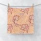 Washcloth with red floral pattern hanging on a line against a white background