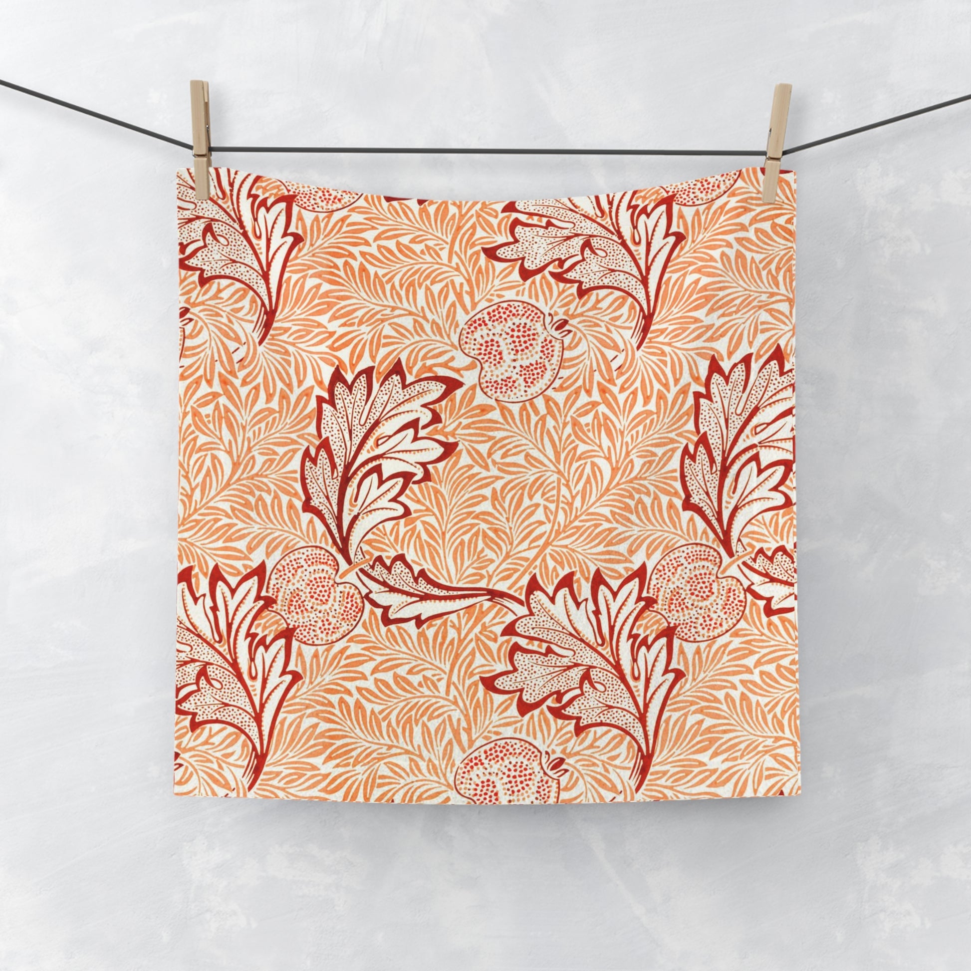 Washcloth with red floral pattern hanging on a line against a white background