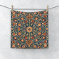 Decorative washcloth with floral pattern hanging on a line against a white background