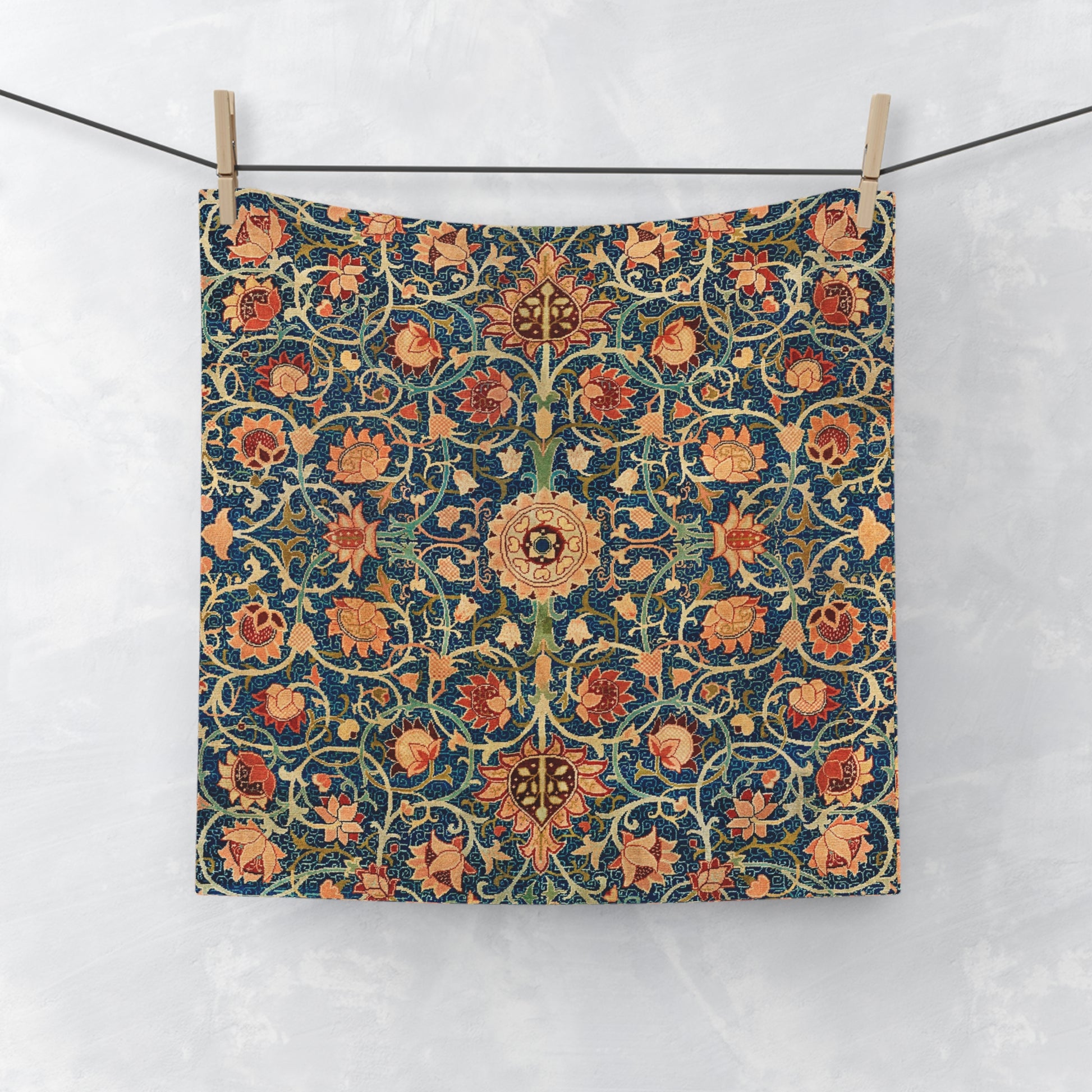 Decorative washcloth with floral pattern hanging on a line against a white background