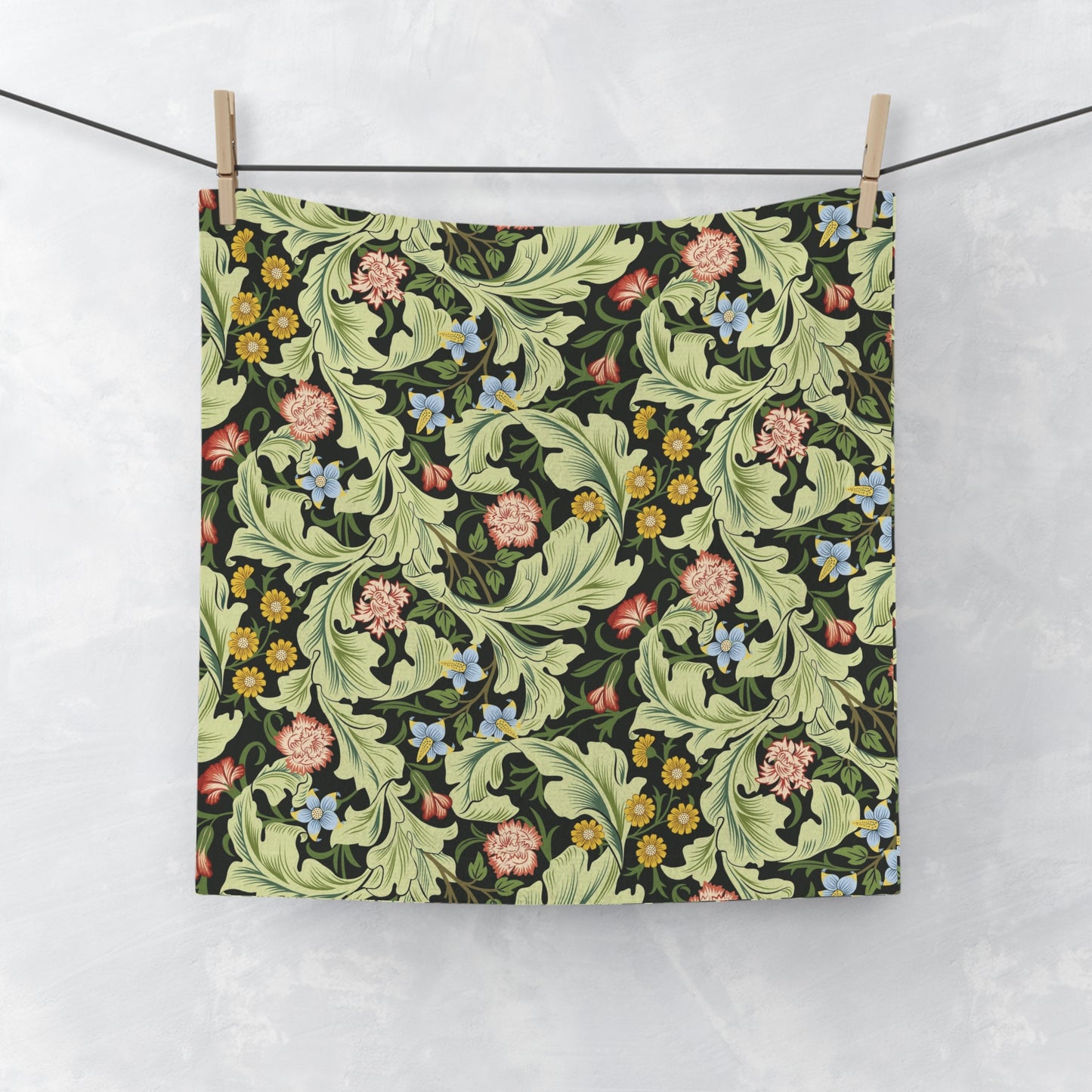 Floral patterned washcloth hanging on a line against a white background