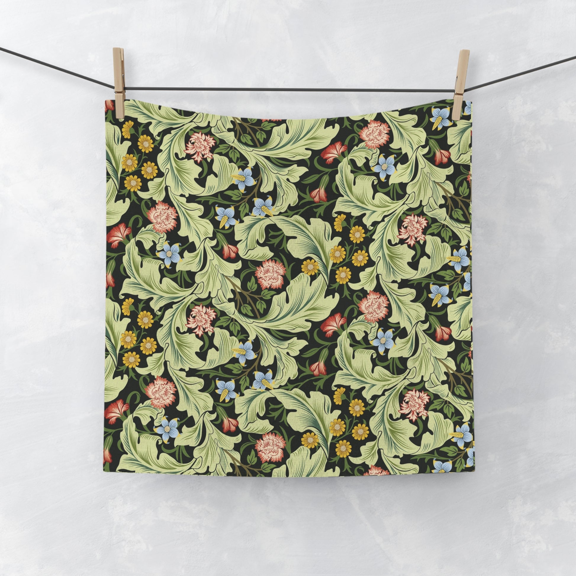 Floral patterned washcloth hanging on a line against a white background