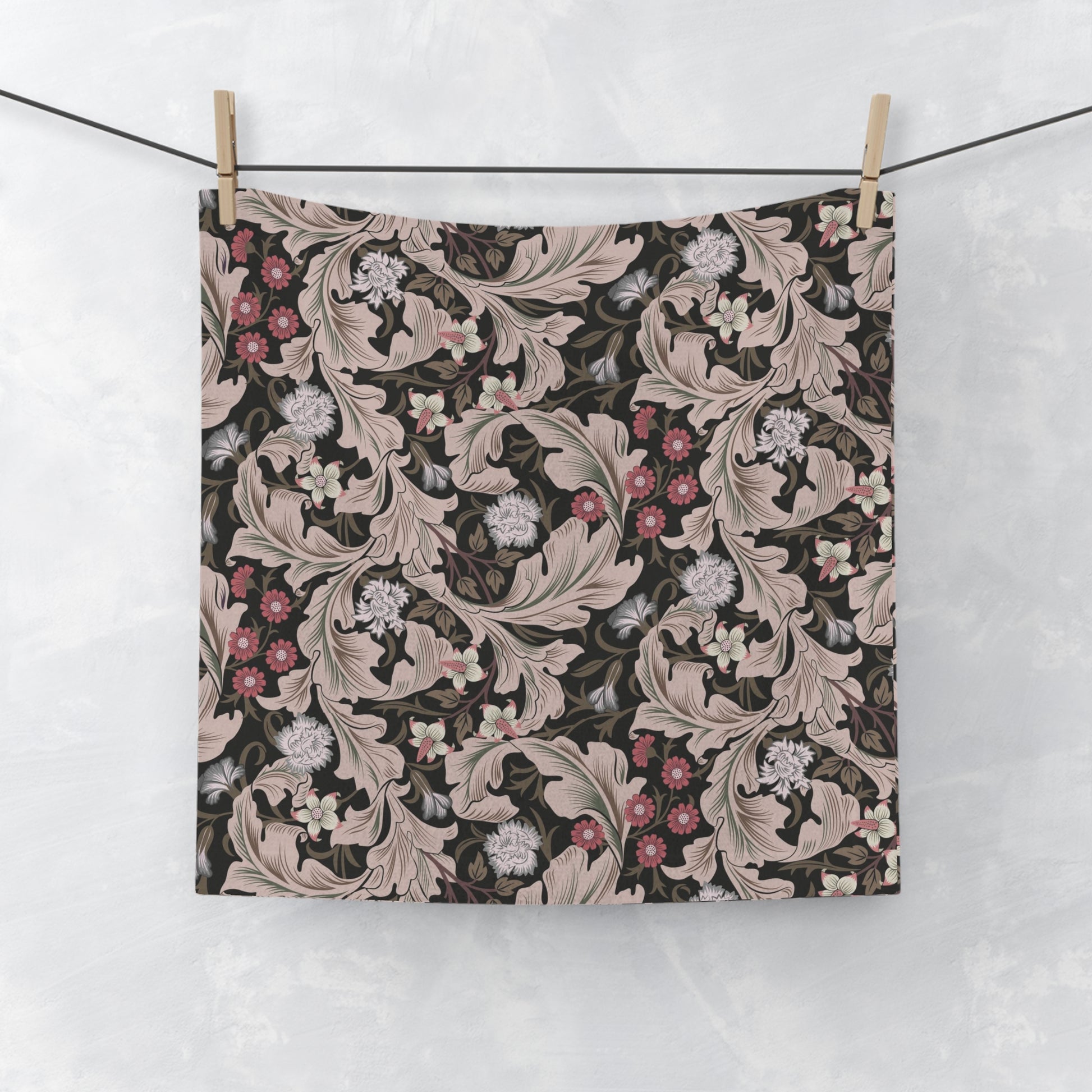 Floral patterned washcloth hanging on a line against a white background