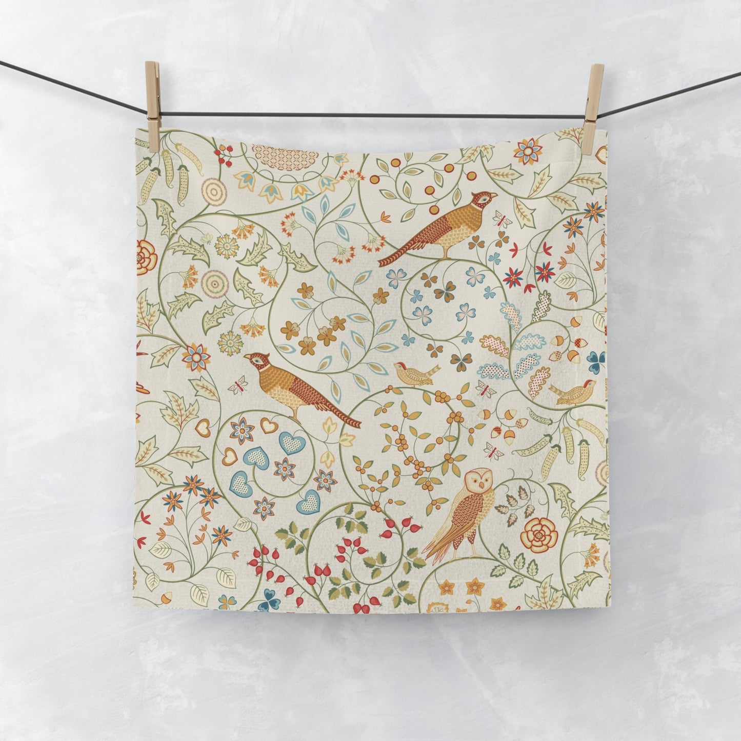Fabric with a floral and bird pattern hanging on a line against a white background