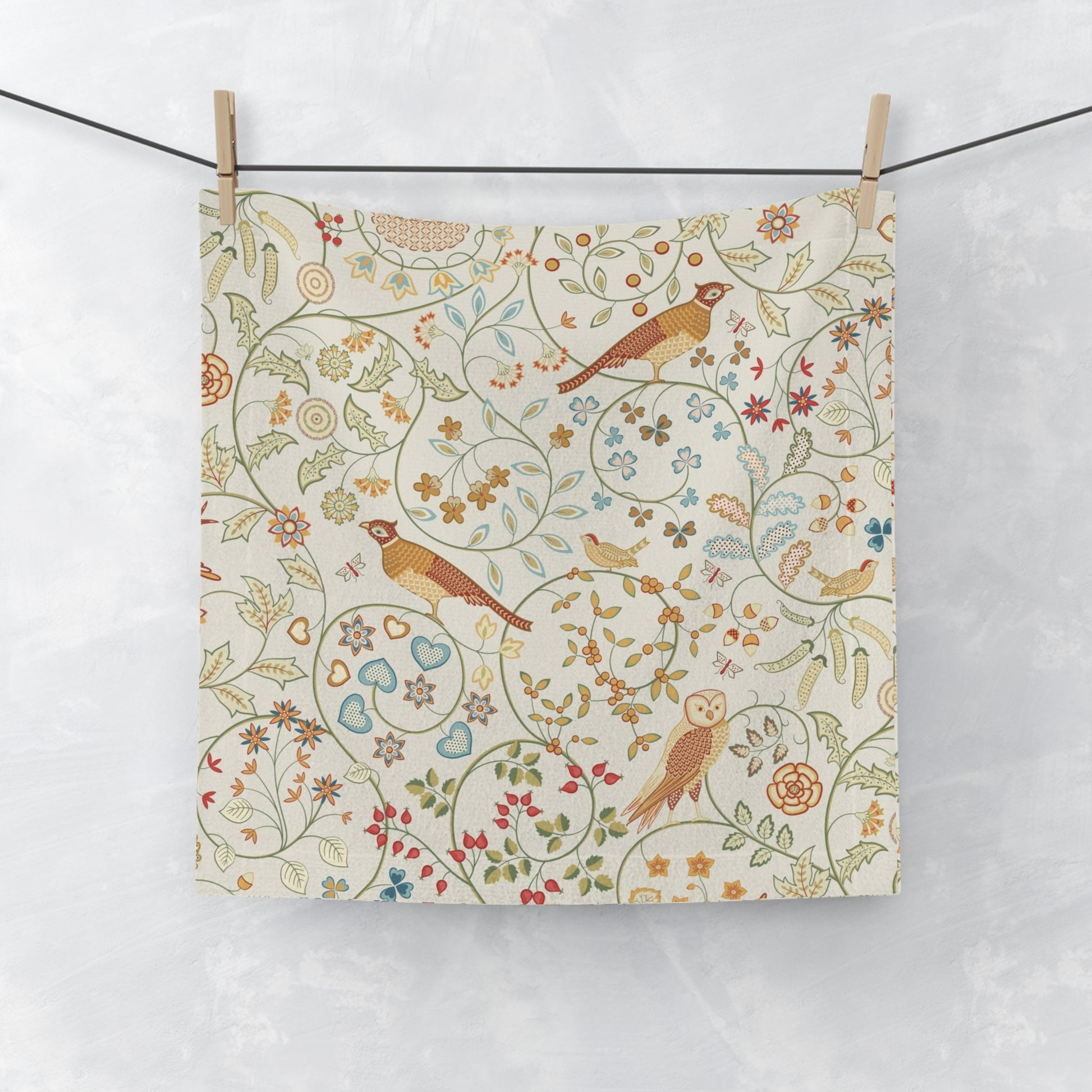 Fabric with a floral and bird pattern hanging on a line against a white background
