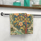 Decorative towel with floral pattern hanging on a towel rack in a bathroom.