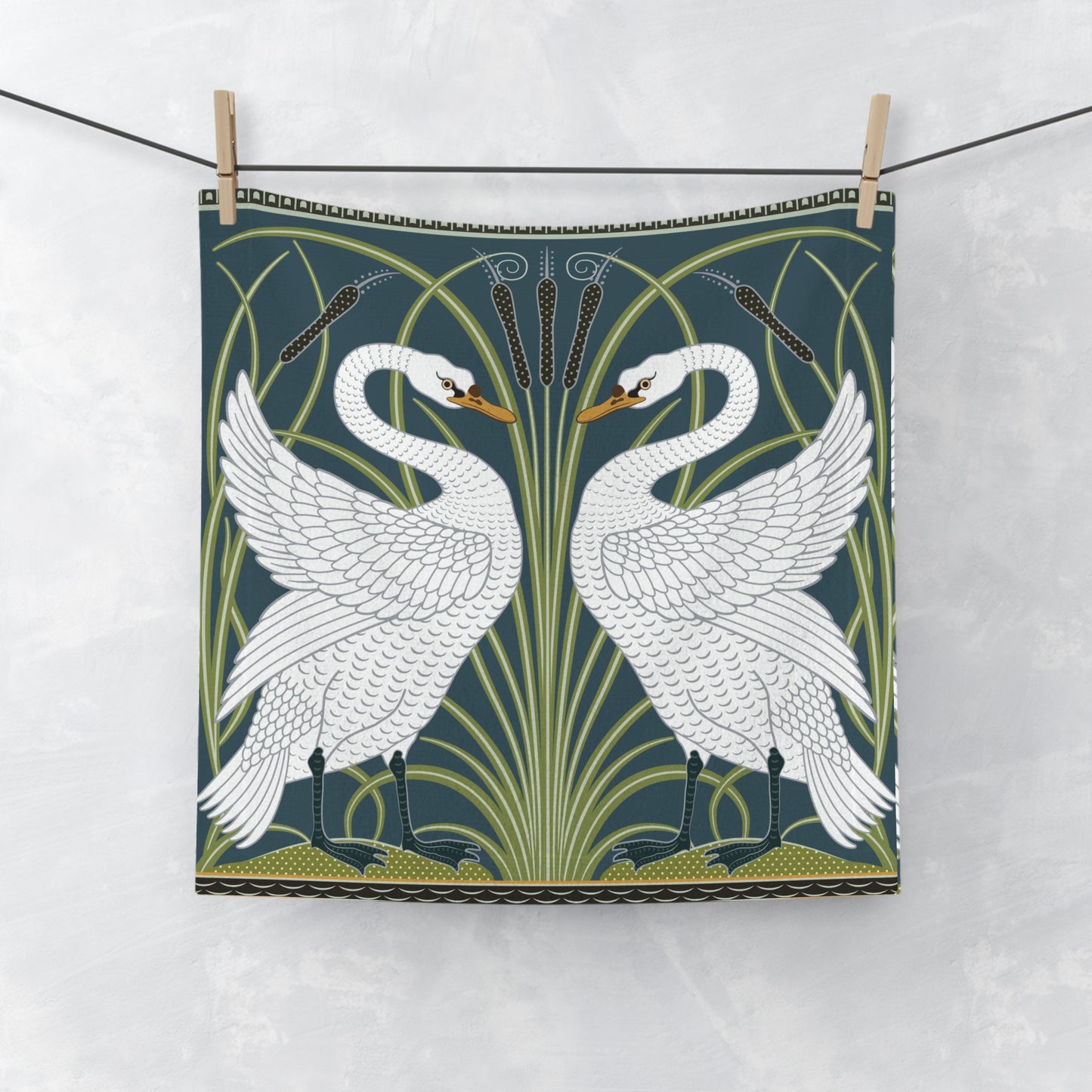 Decorative towel with white swan design on a green background, hanging on a line.