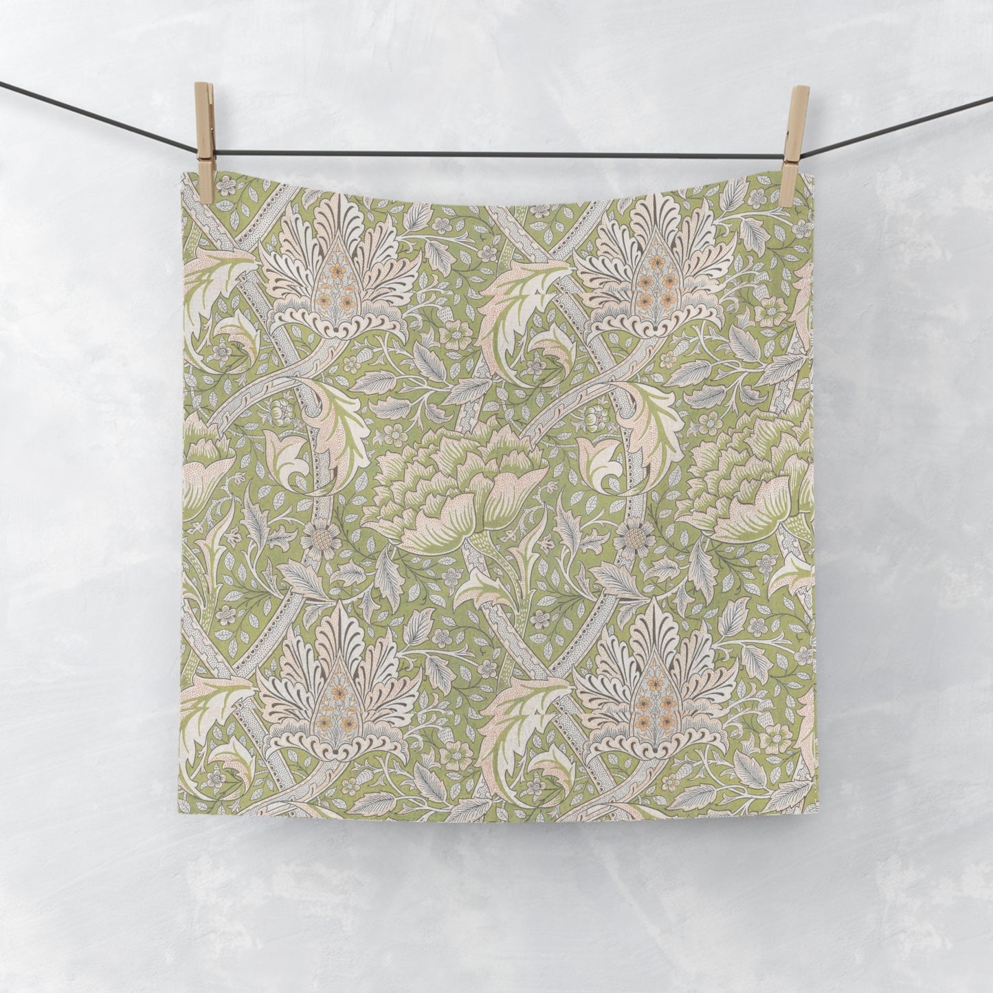 Floral patterned wqshcloth hanging on a line against a white background