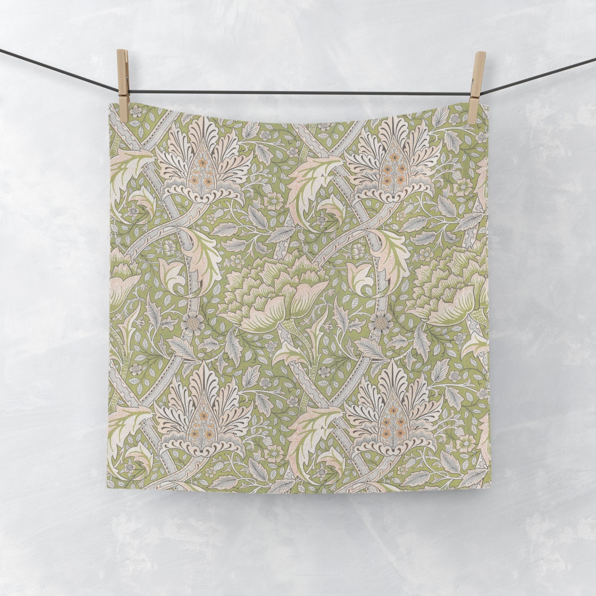 Floral patterned wqshcloth hanging on a line against a white background