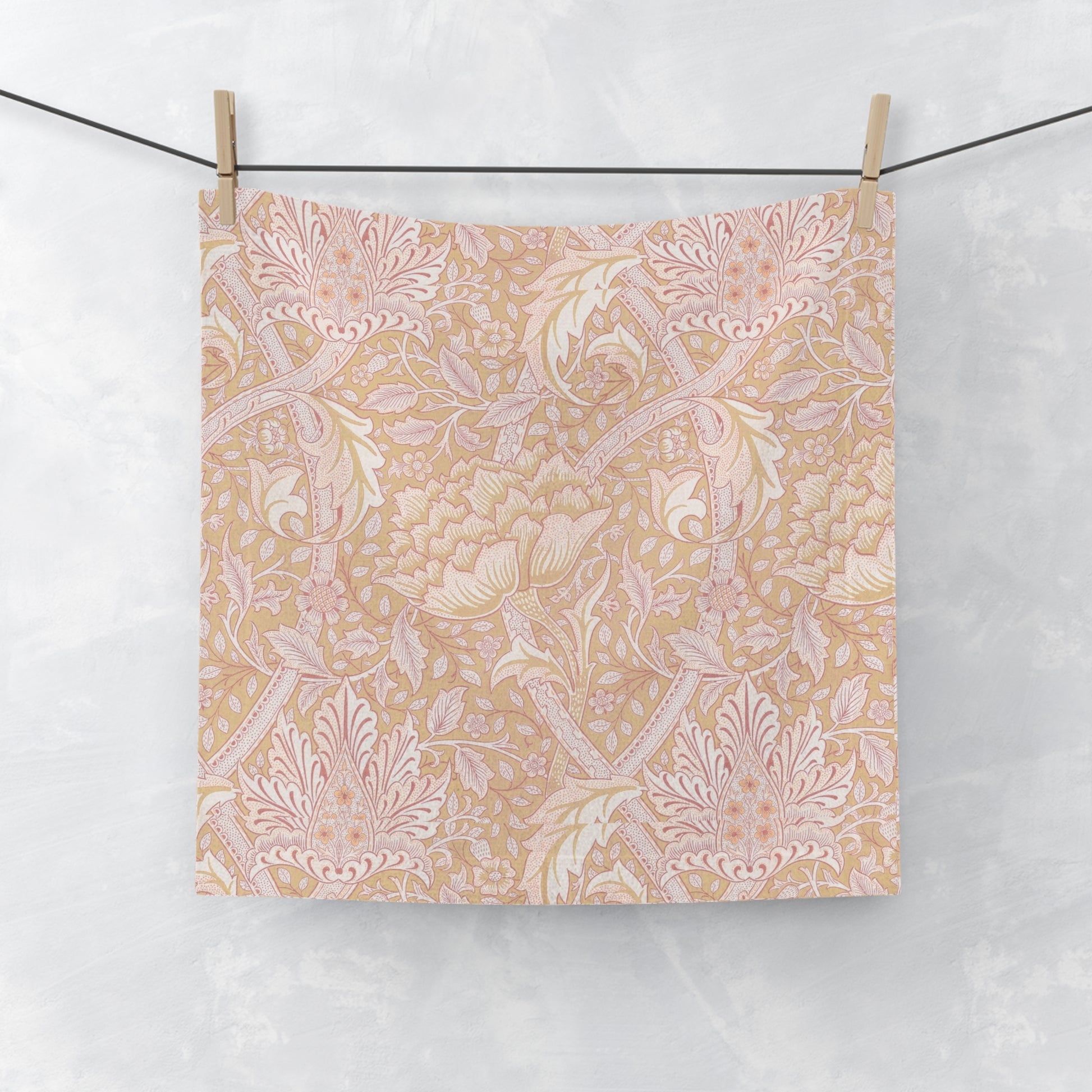 Floral patterned washcloth hanging on a wire with a white background