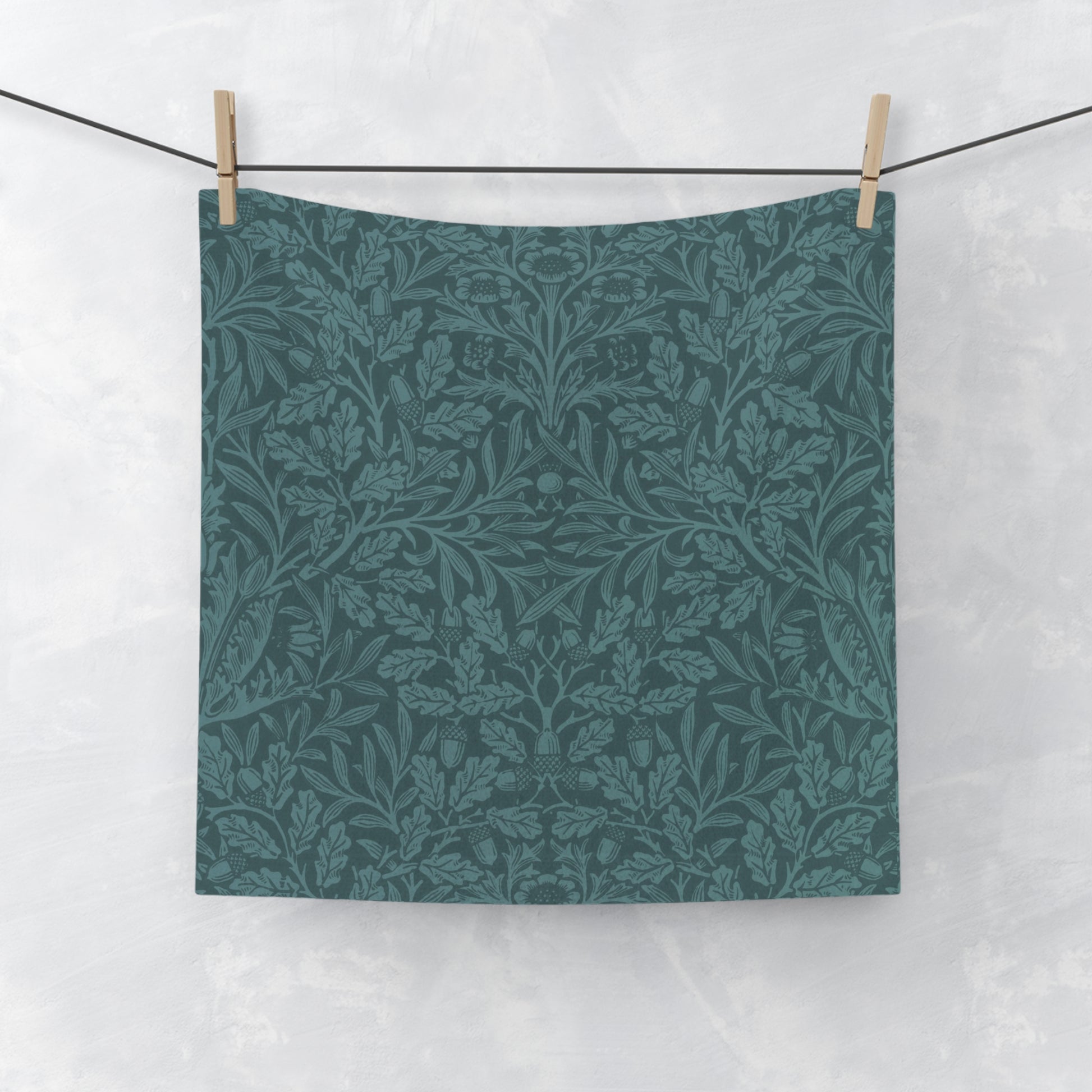 A square-shaped washcloth with a floral pattern in a teal colour, inspired by William Morris' Acorns & Oak Leaves Collection.