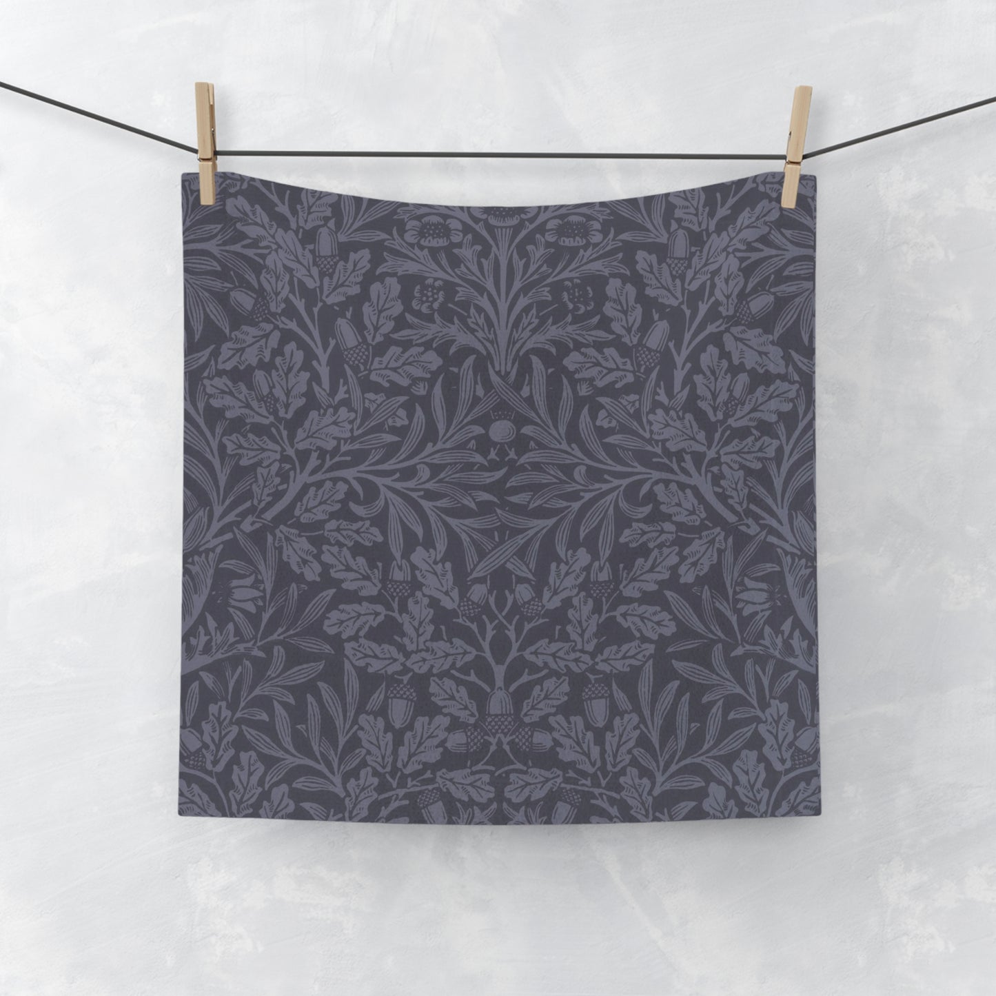 A smoky blue washcloth with a floral pattern inspired by William Morris's design, featuring acorns and oak leaves.