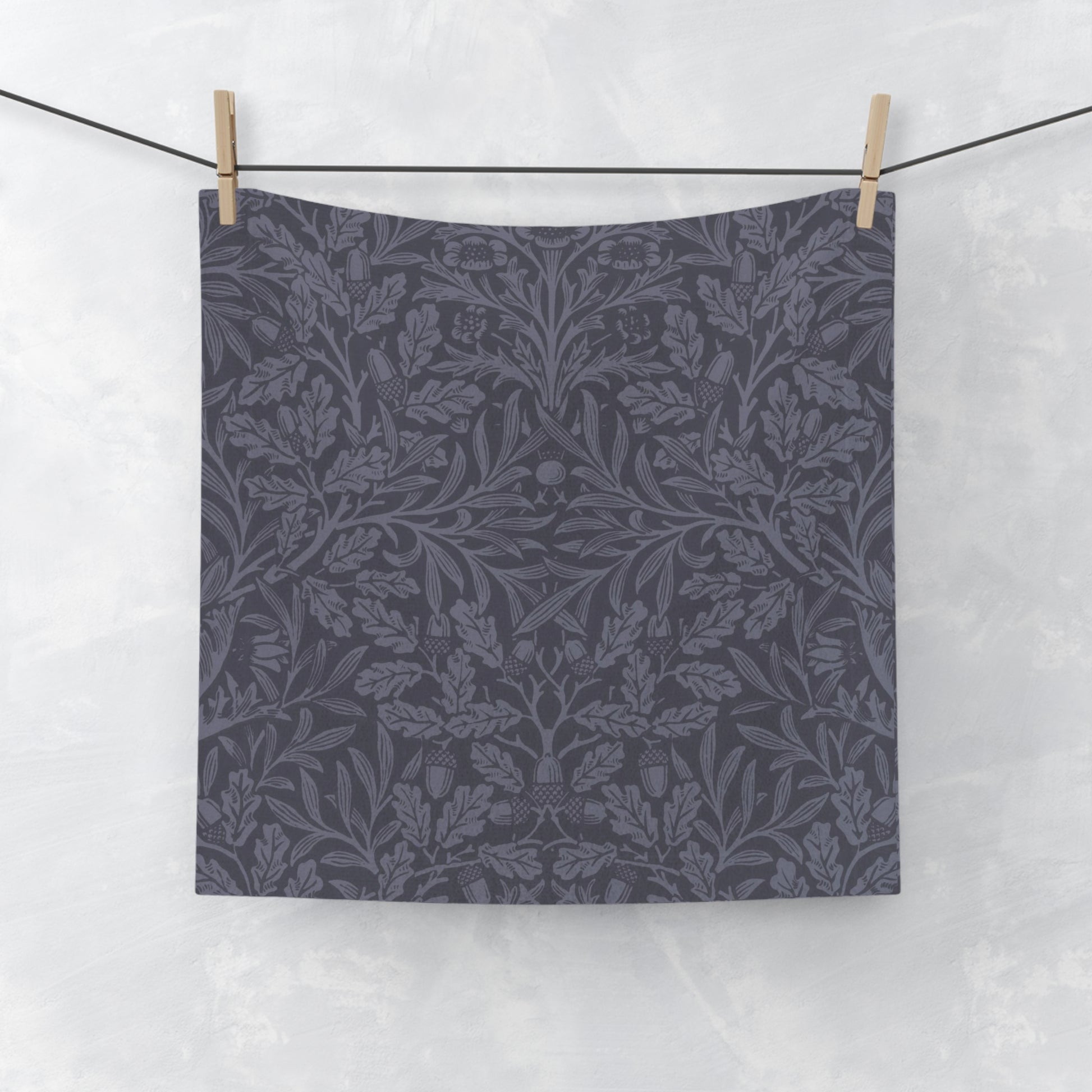 A smoky blue washcloth with a floral pattern inspired by William Morris's design, featuring acorns and oak leaves.