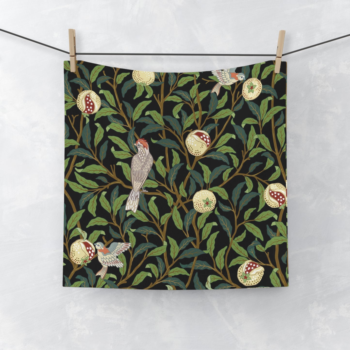 A white washcloth with a floral pattern featuring birds and pomegranates, inspired by the William Morris design.