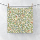 A white washcloth with a floral pattern inspired by William Morris, featuring birds and pomegranate designs on a parchment background.