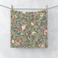 A white washcloth with a floral pattern featuring birds and pomegranates, inspired by William Morris' Bird & Pomegranate Collection.