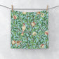 A washcloth with a floral William Morris & Co pattern featuring birds and pomegranates on a Tiffany Blue background.