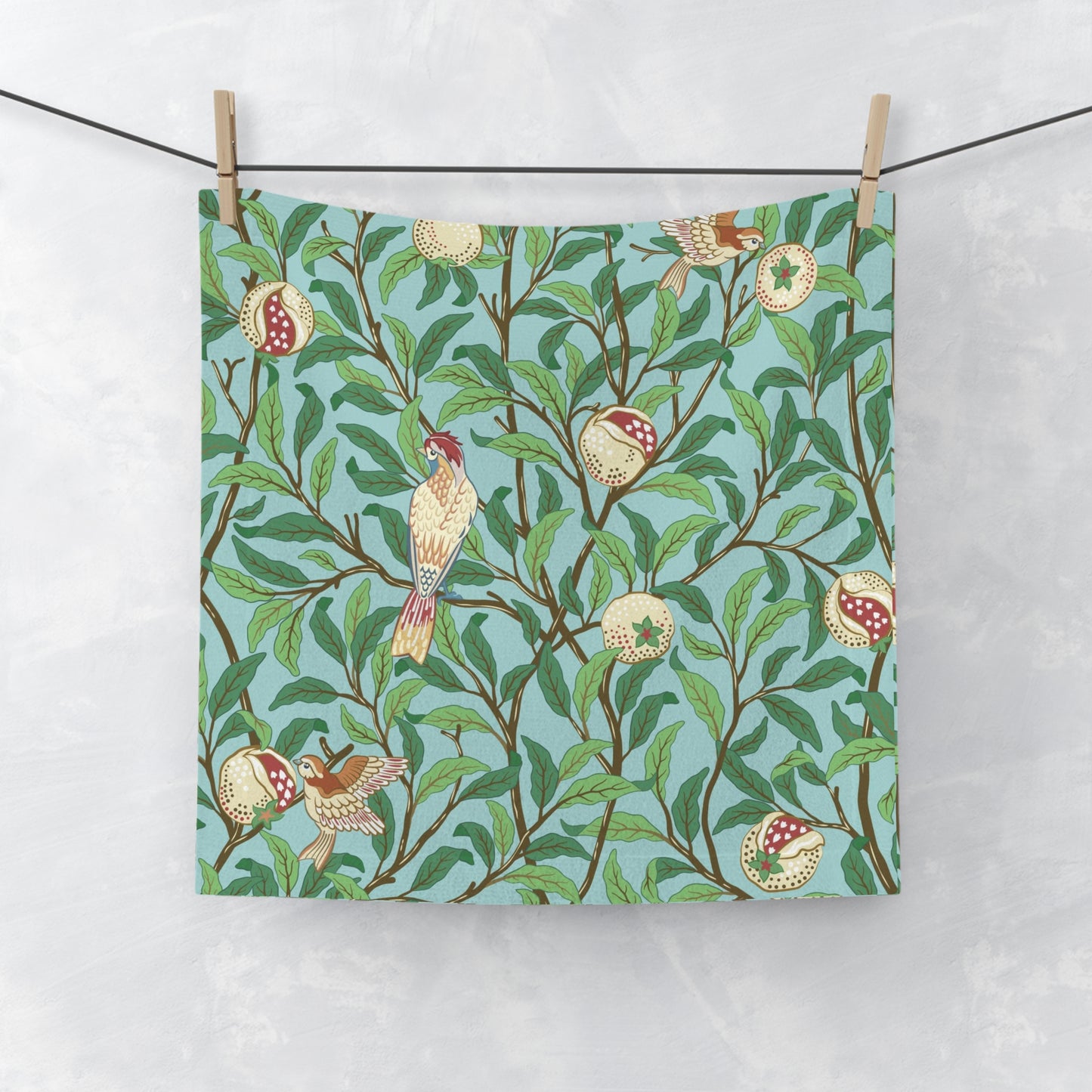 A washcloth with a floral William Morris & Co pattern featuring birds and pomegranates on a Tiffany Blue background.
