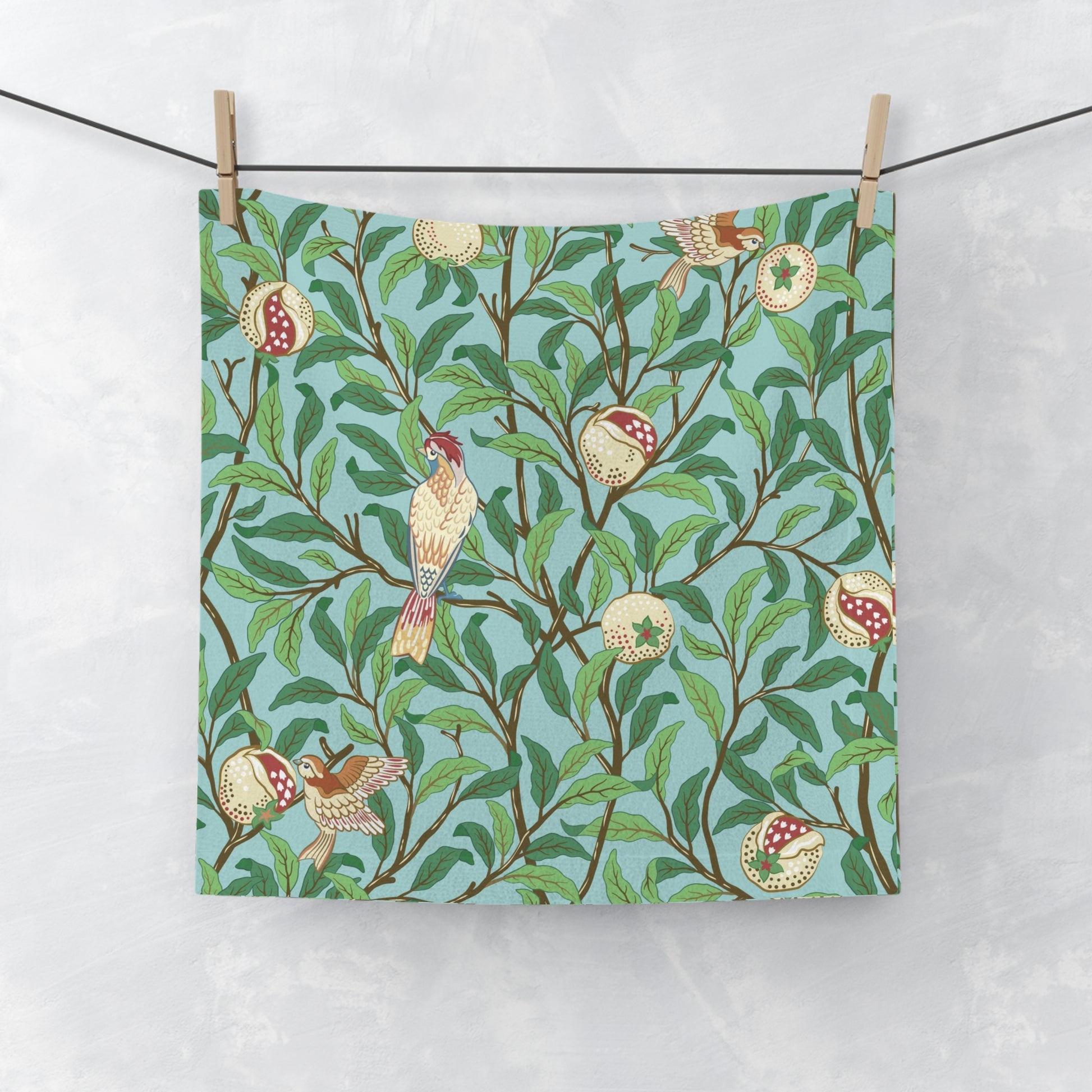 A washcloth with a floral William Morris & Co pattern featuring birds and pomegranates on a Tiffany Blue background.