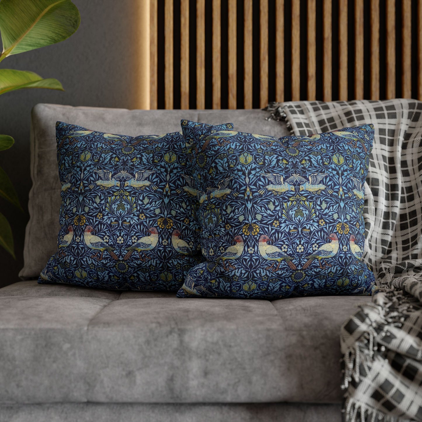 Decorative pillows with a floral pattern on a gray sofa against a wooden panel background.