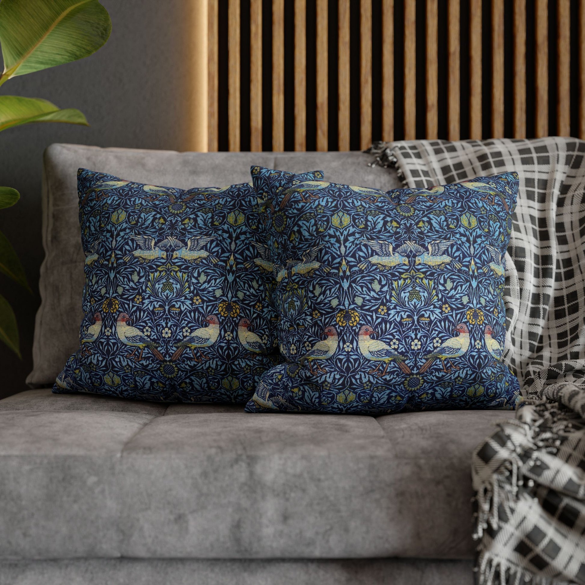 Decorative pillows with a floral pattern on a gray sofa against a wooden panel background.