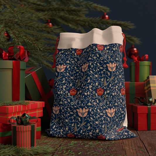 A Christmas Santa Sack with a navy background featuring an intricate floral pattern in white and red, with a cream-coloured top and red drawstrings.