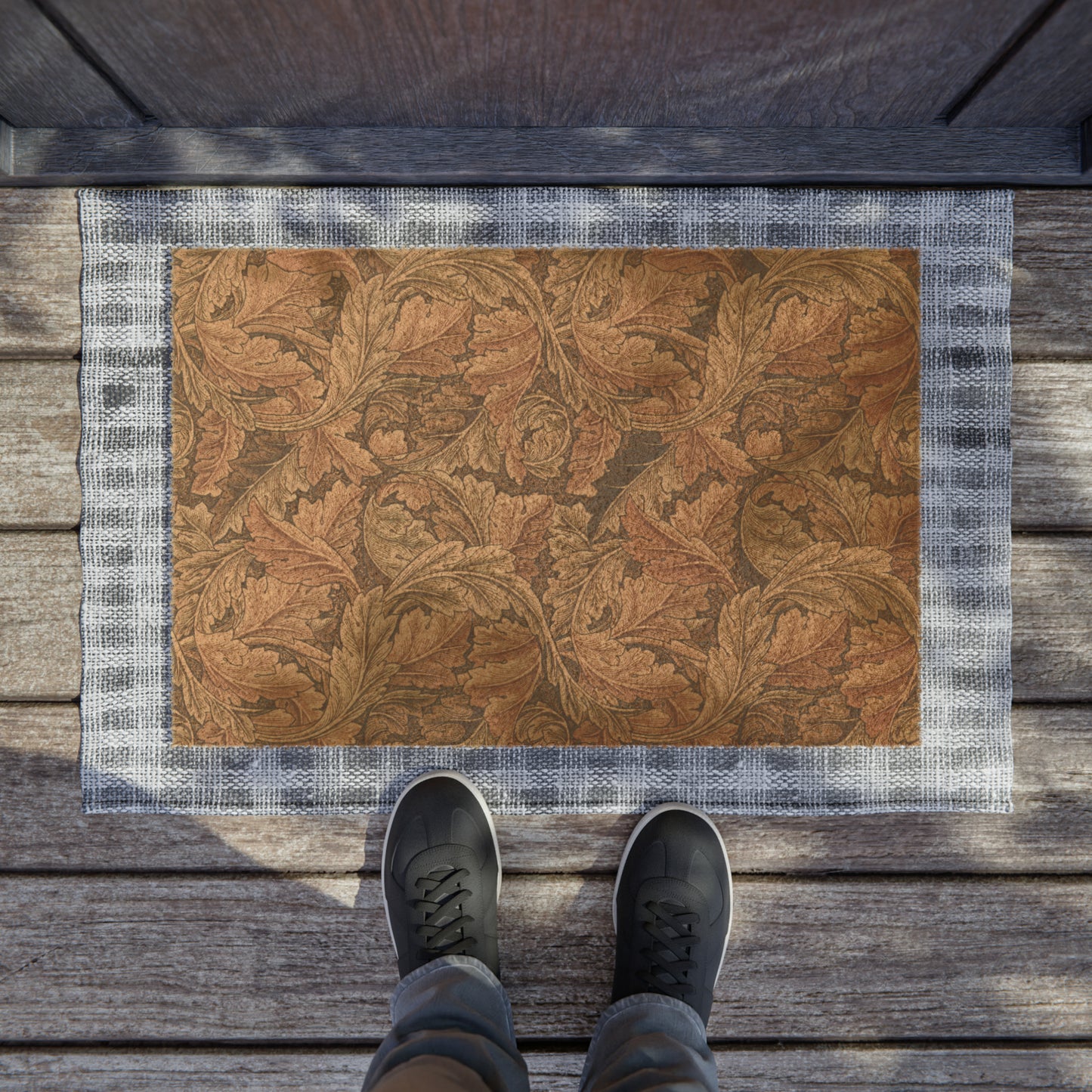 A rectangular coconut coir doormat with an intricate brown leaf William Morris & Co pattern and a solid black vinyl backing, designed for indoor and outdoor use.