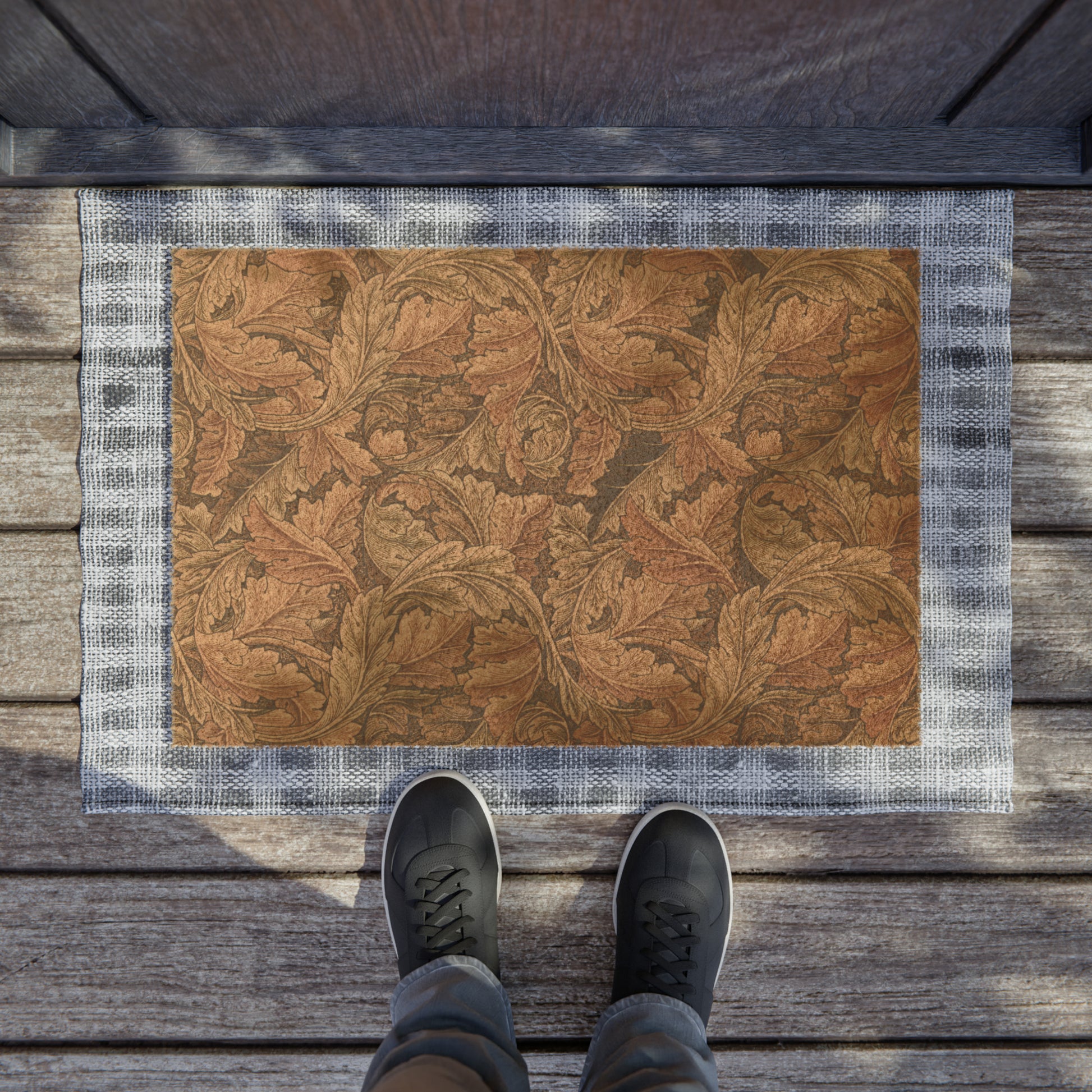 A rectangular coconut coir doormat with an intricate brown leaf William Morris & Co pattern and a solid black vinyl backing, designed for indoor and outdoor use.