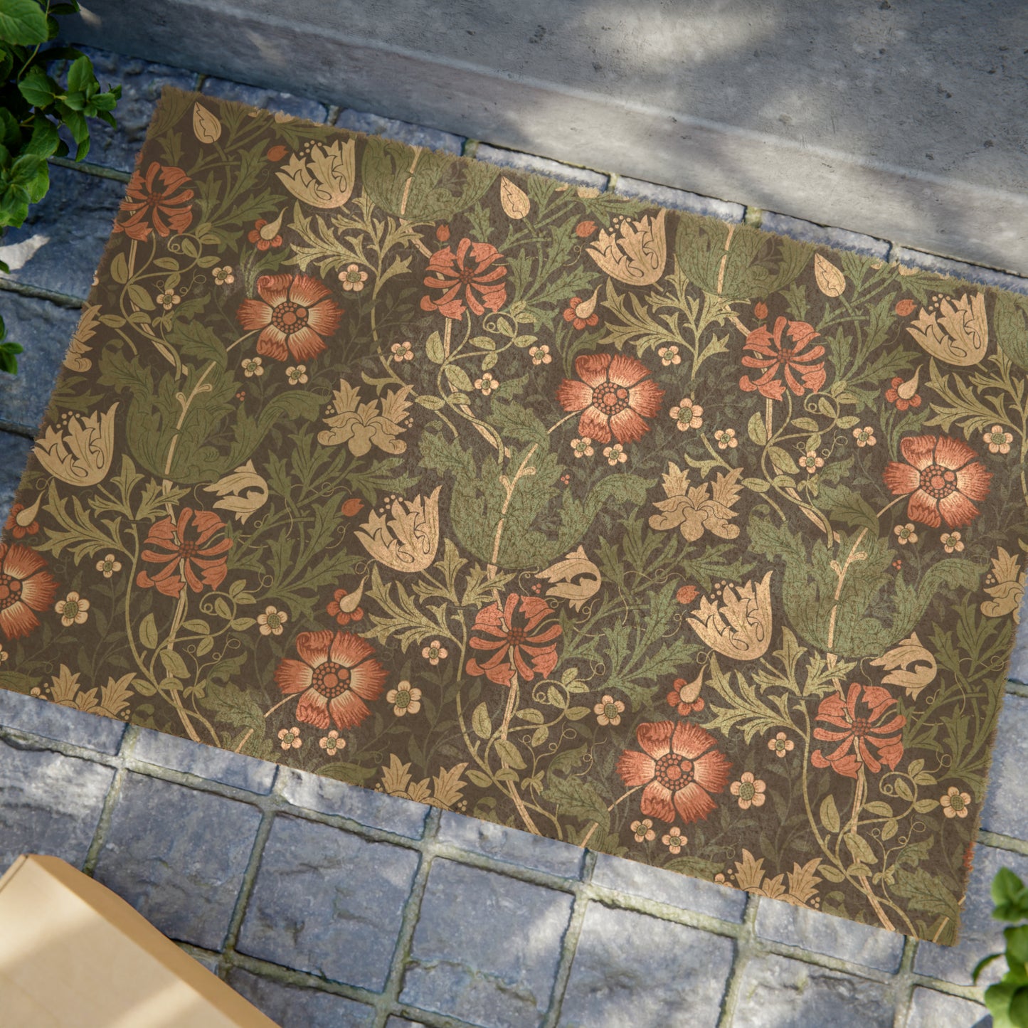 A rectangular coconut coir doormat with a floral pattern inspired by William Morris's designs, featuring a green background with multi-coloured flowers.