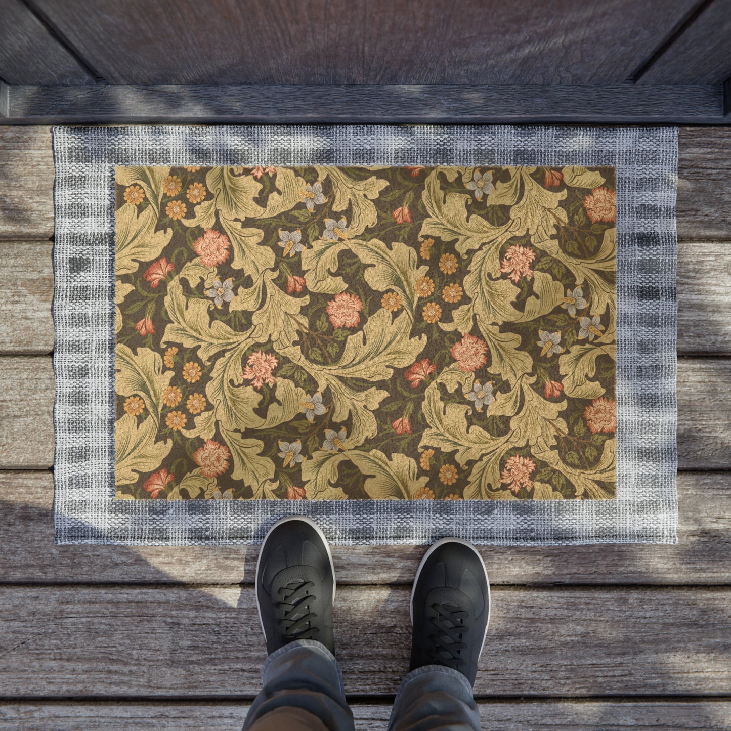 A rectangular coconut coir doormat with an intricate floral William Morris & Co pattern in green and brown colours, featuring a black vinyl backing.