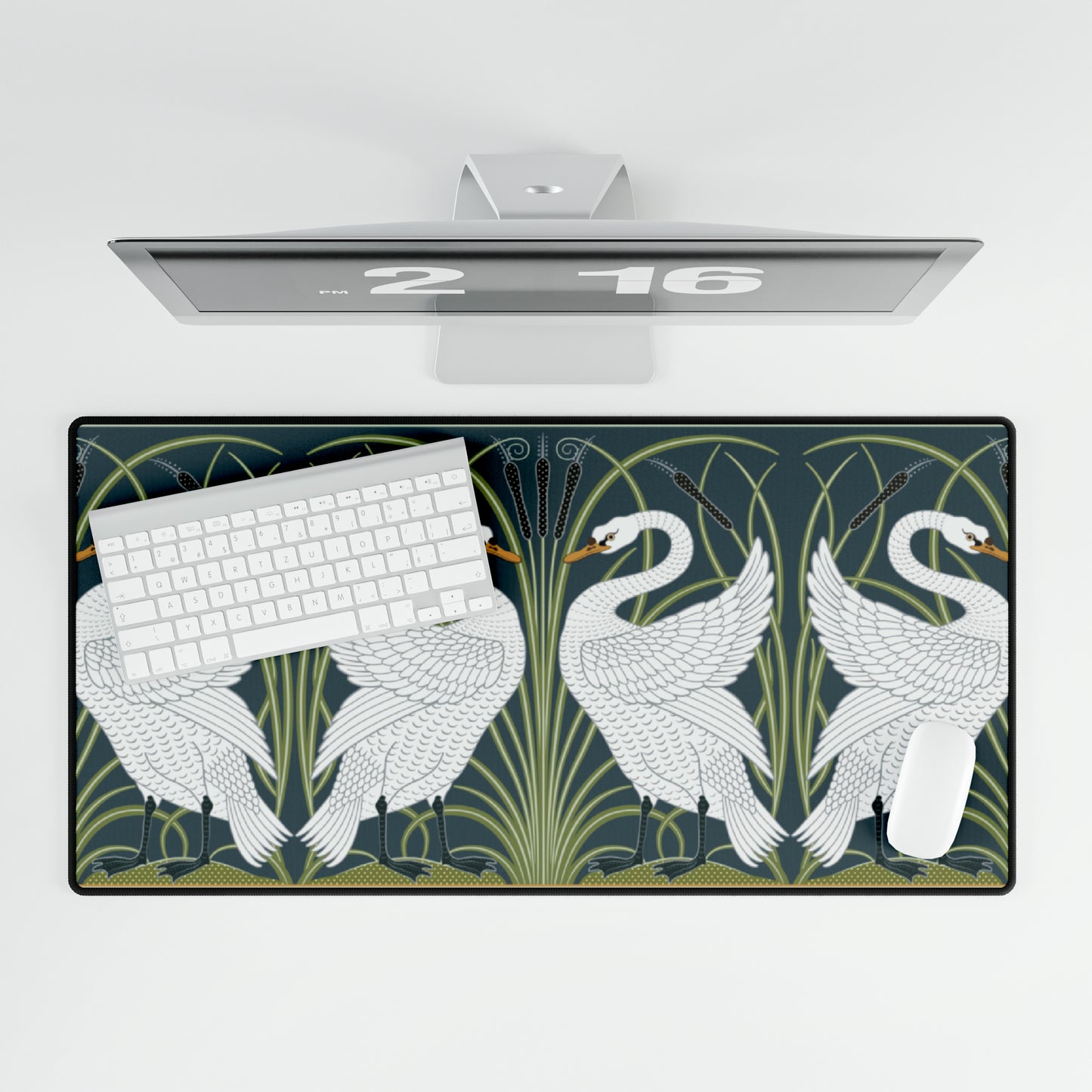 A rectangular desk mat with a floral and swan William Morris & Co pattern design, featuring a white background and swans, placed under a white mouse pad with a keyboard on top.