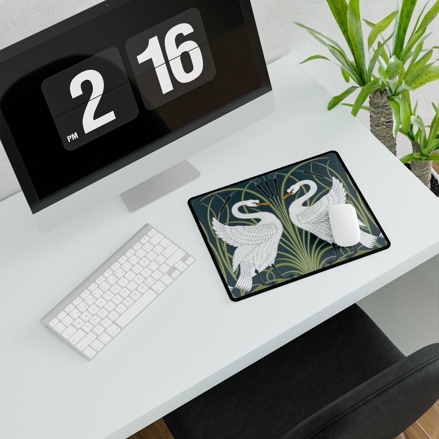 A rectangular desk mat with a floral and swan William Morris & Co pattern design, featuring a white background and swans, placed under a white mouse pad with a keyboard on top.